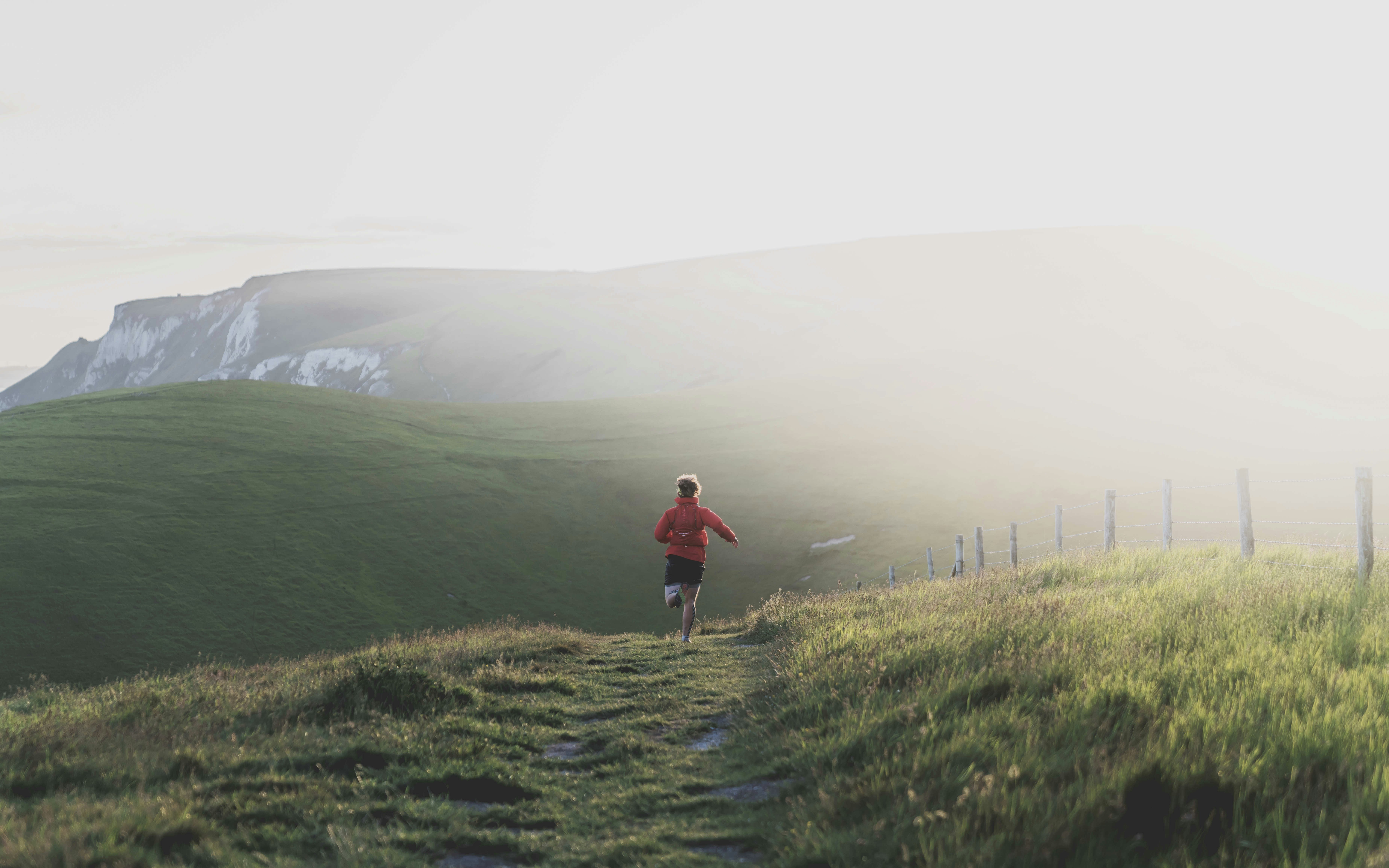 Trail runner heading up a misty hillside